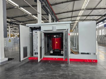 Open electrical cabinet with red transformer inside in a spacious industrial facility.