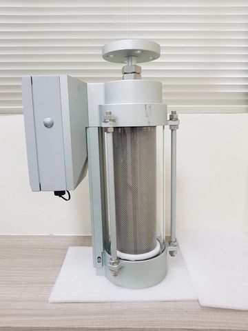 Metal cylindrical device with control box and bolts on a table.