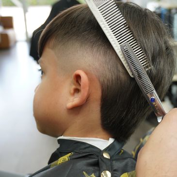 Young boy getting a haircut with scissors and comb.