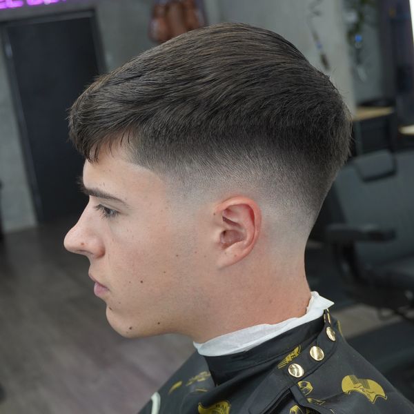 Men's haircut with a fade and short fringe.