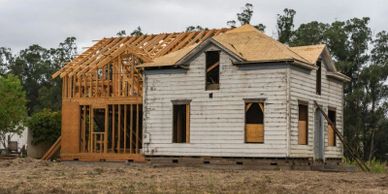 A house under renovation with new framing and roofing in progress.