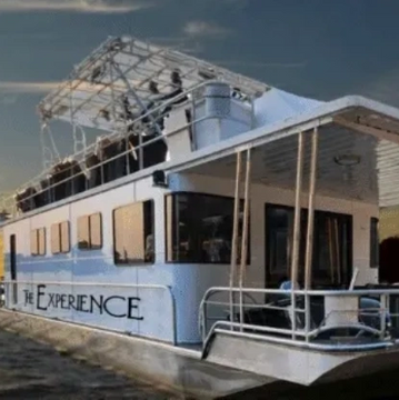 A large boat named 'The Experience' on calm water at sunset.