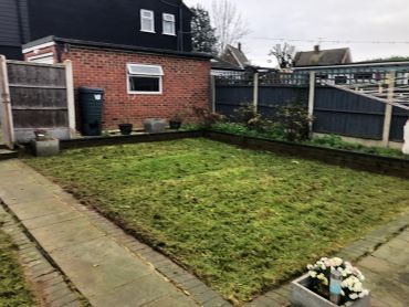 A backyard with a small lawn and paved pathway.