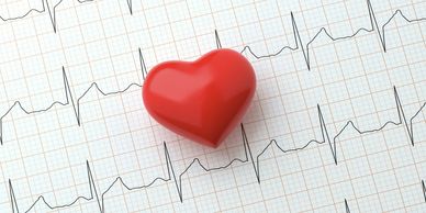 Red heart model on an electrocardiogram (ECG) printout.