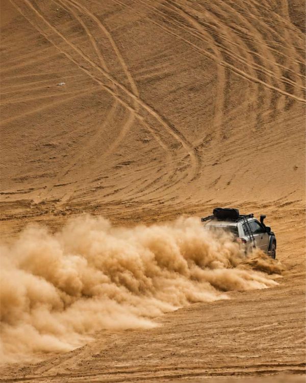 Vehículo todoterreno levantando polvo en el desierto.