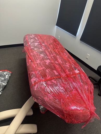 Office chair wrapped tightly in red plastic wrap.