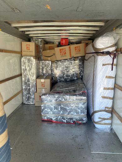 Packed moving truck with wrapped furniture and boxes.