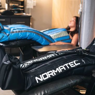 Person using Normatec compression boots for recovery.