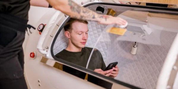 Man inside a hyperbaric chamber using his phone.