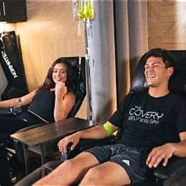 Two people donating blood, sitting comfortably.