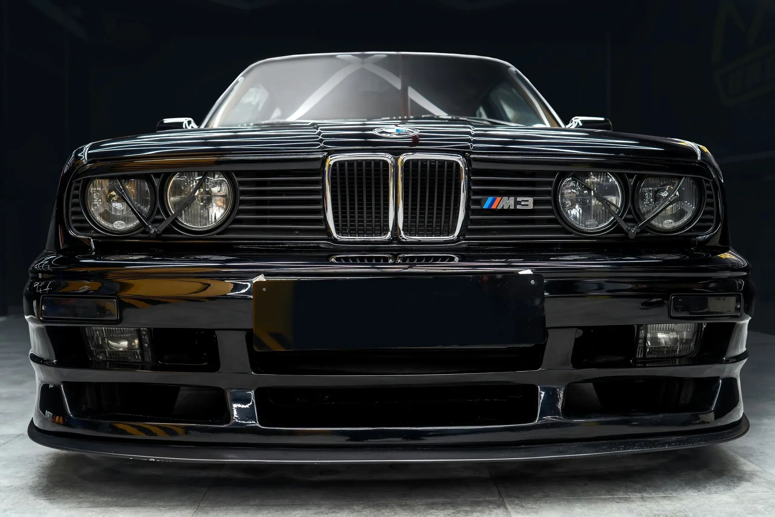 Front view of a black BMW M3 with distinctive headlights and grille.