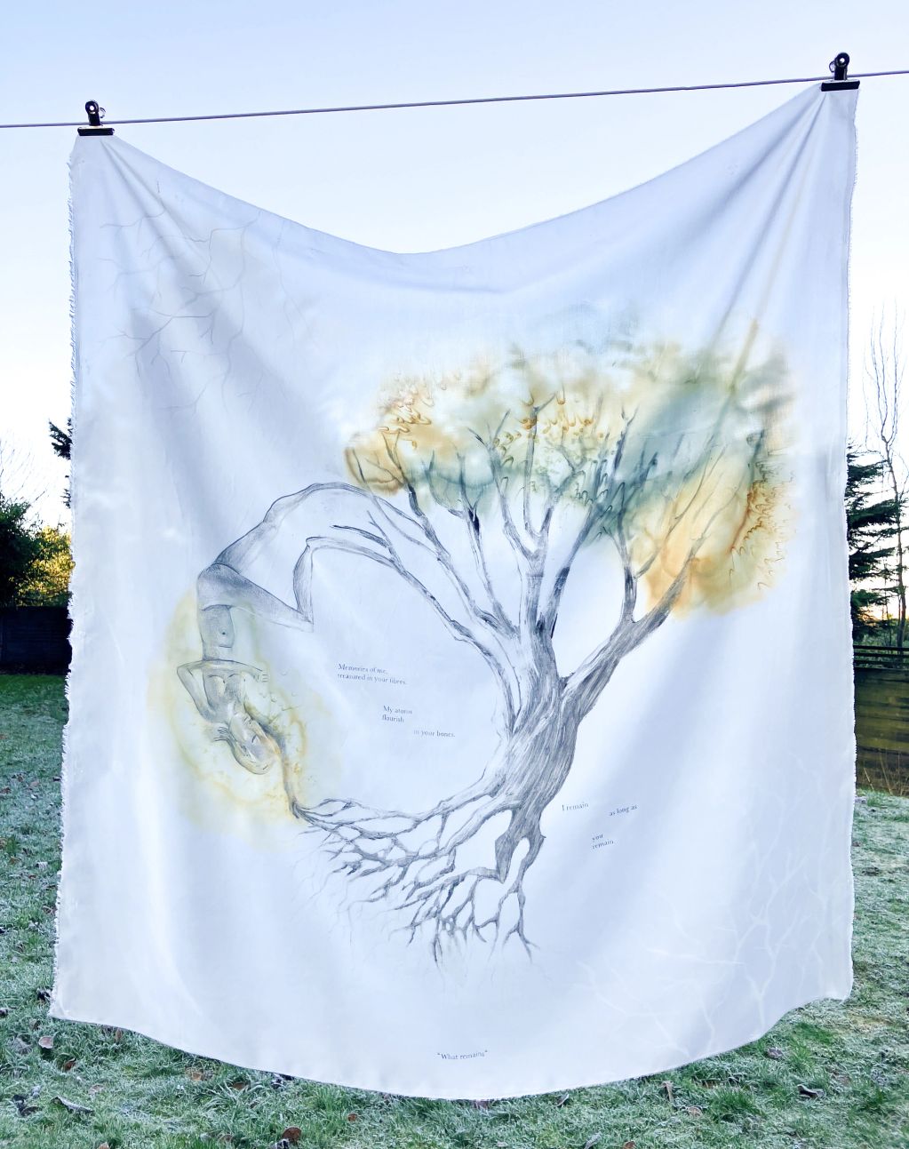 A cloth with a tree and upside-down person artwork hanging on a line.