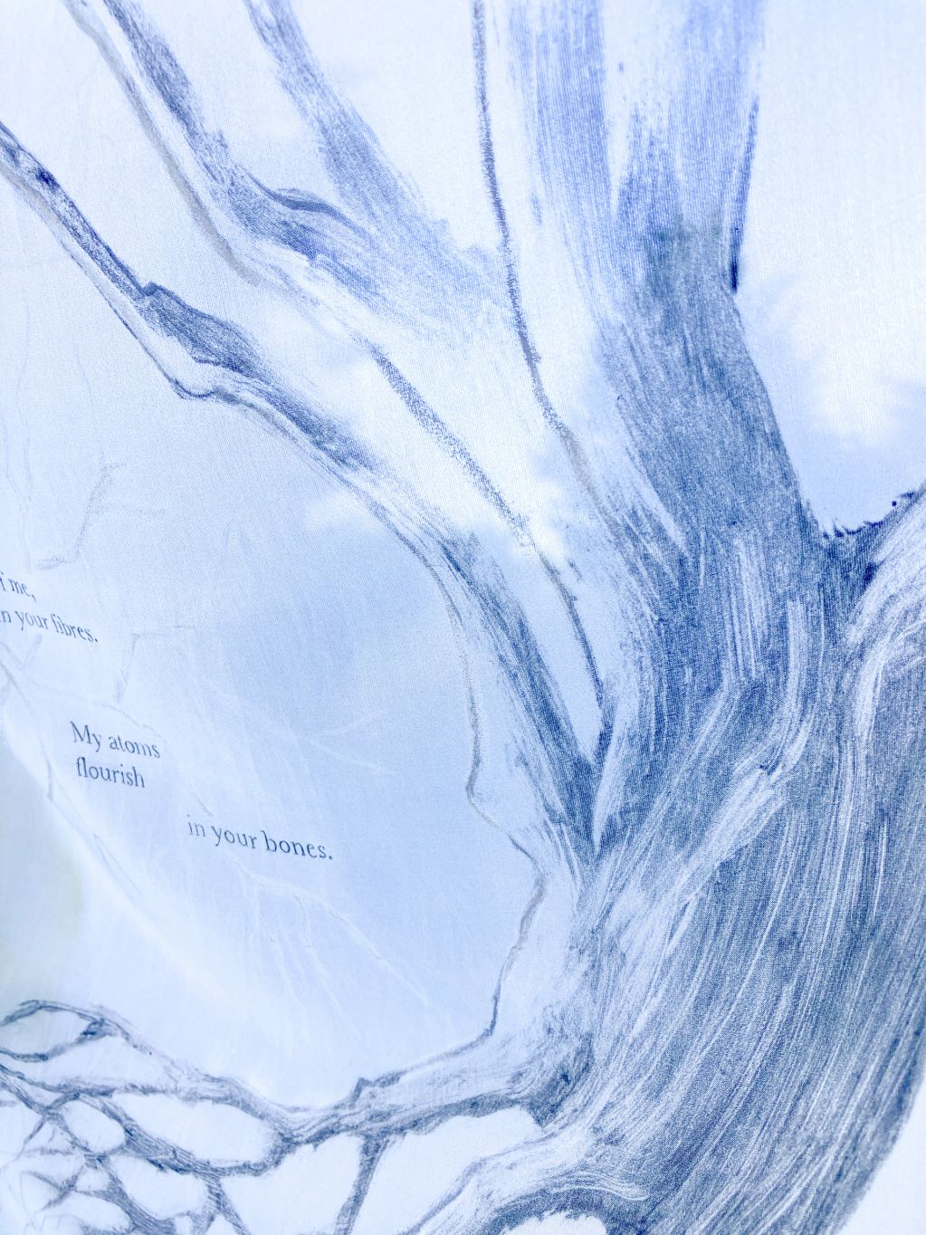 Blue sketch of a tree with poetic text on fabric.