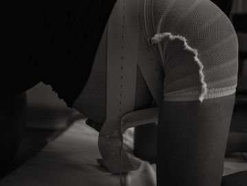 Black and white image of a person wearing a textured garment, bent forward.