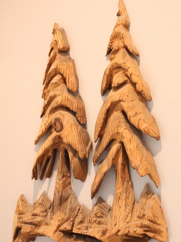 Wooden wall art carving of two pine trees with textured details.