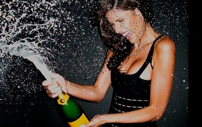 Young lady smiling, and opening a bottle of champagne 