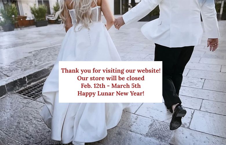 A groom lifts and kisses his bride in a sunlit rustic street.