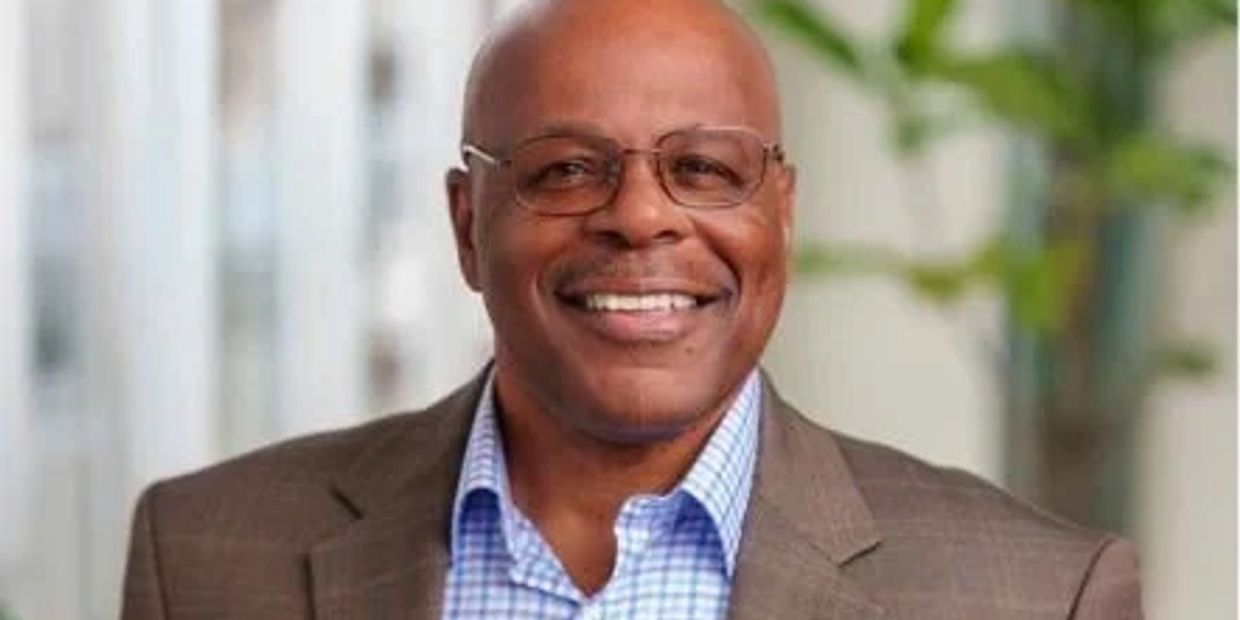 Smiling man in glasses and suit jacket.