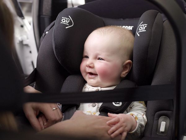 Smiling baby securely fastened in a car seat with superior air protection.