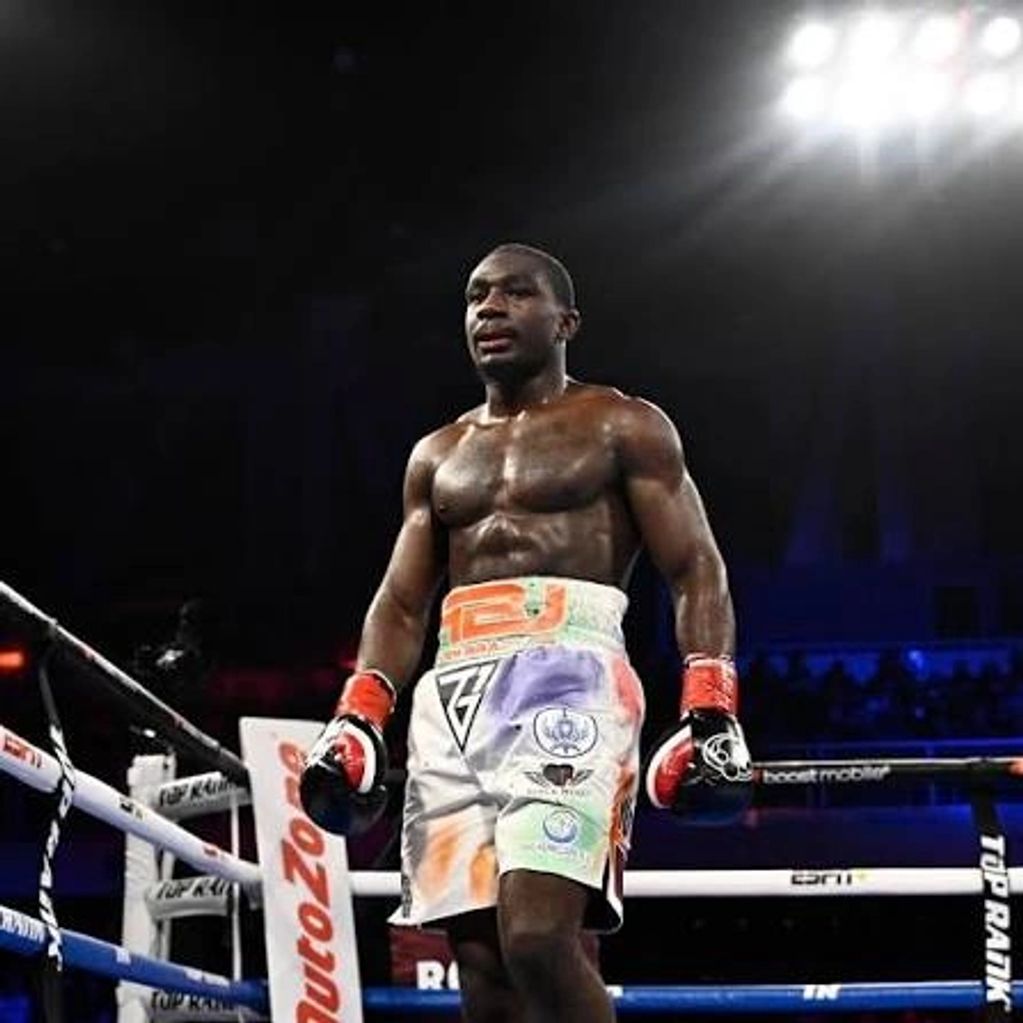 Boxer standing confidently in the ring wearing colorful shorts and gloves.