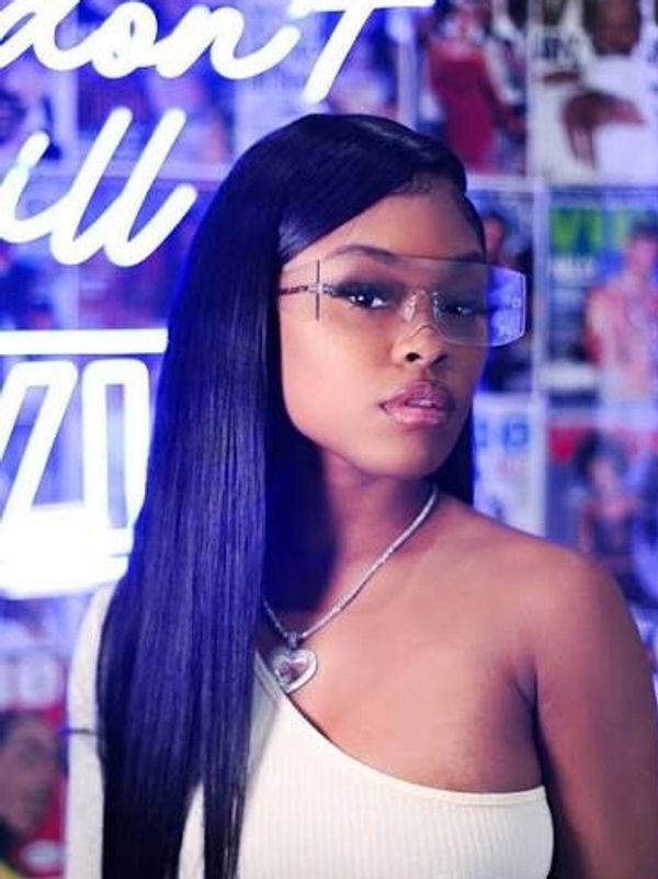Woman with long straight hair and transparent glasses poses confidently.