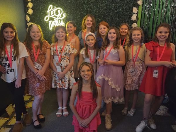 A group of girls pose at the greenery wall during a birthday party at Chelsea Party Loft. 