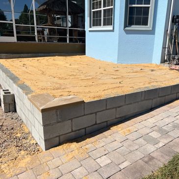 Leveled sand base and retaining wall prepared for a residential patio installation.