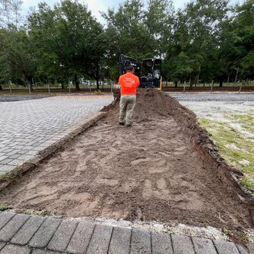Crew member grading and leveling a driveway preparation area.