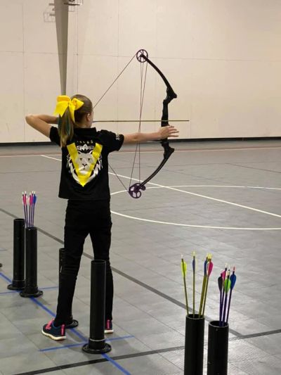 Young girl practicing archery indoors.