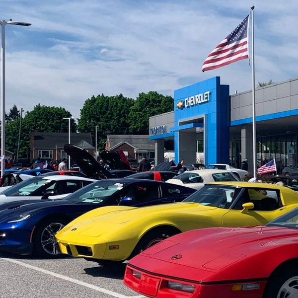 Classic and modern sports cars lined up at a Chevrolet dealership car show.