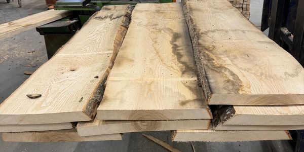 Gestapelde ruwe houten planken in een werkplaats.