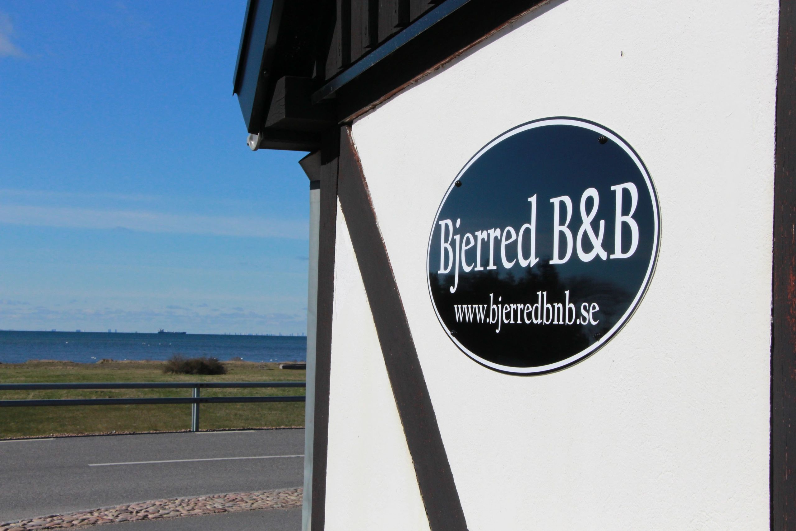 Sign for Bjerred B&B on a building near the sea.