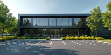 Modern black office building with large glass windows and empty parking spaces.