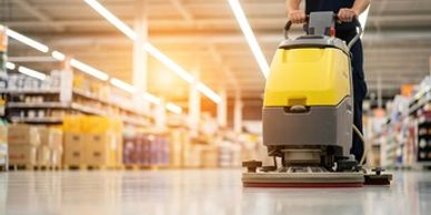 Person using a floor cleaning machine in a large store.