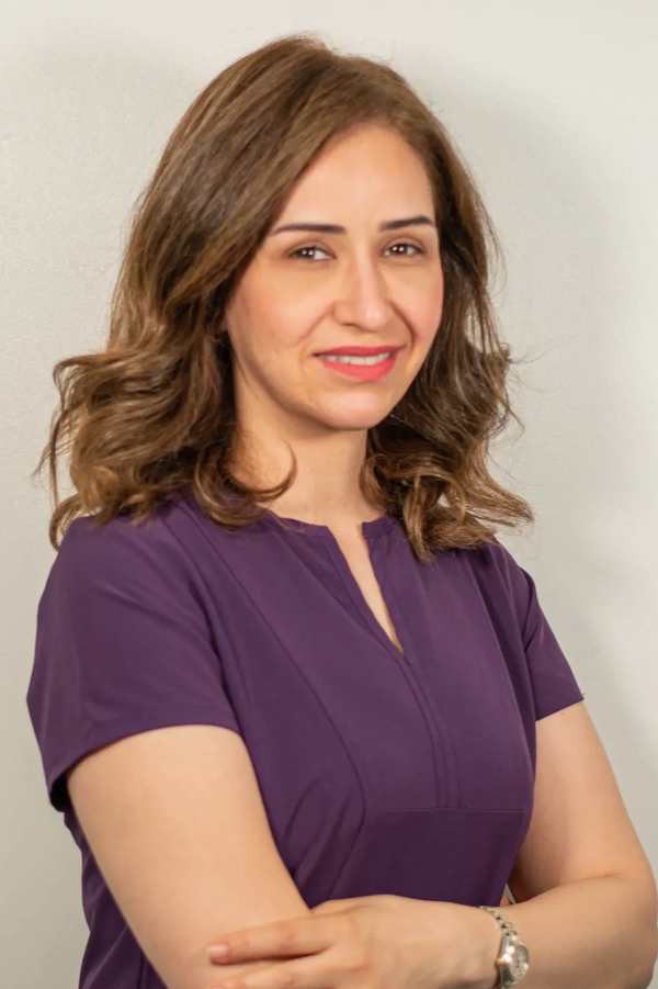 a woman with brown hair wearing a purple blouse