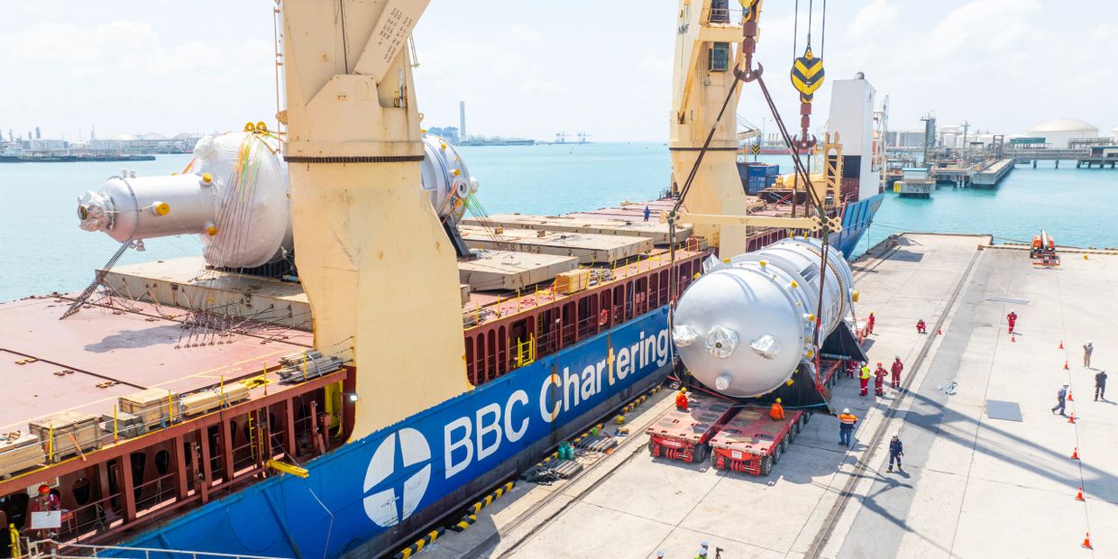Large industrial equipment being unloaded from a BBC Chartering ship at a port.