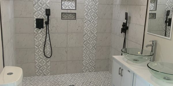 Modern bathroom with dual showers, glass vessel sinks, and patterned tiles.