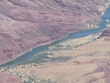 Aerial view of a winding river through rocky terrain and sparse vegetation.