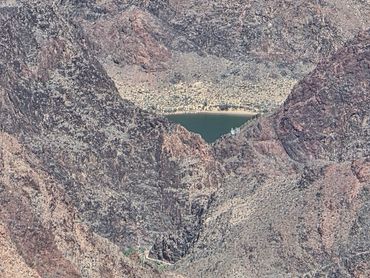 A hidden lake nestled within rugged mountain terrain.
