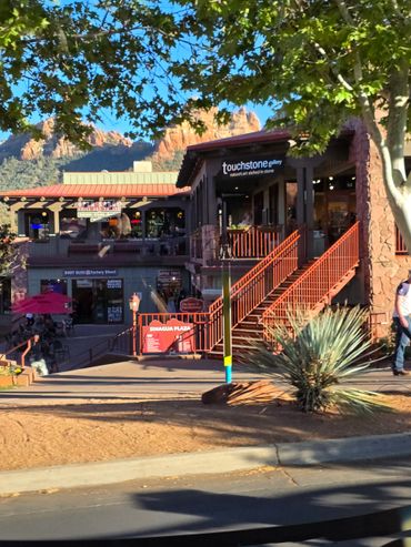 Outdoor shopping area with rustic buildings and red rock backdrop.