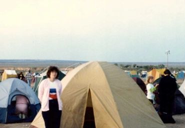 People camping with tents set up in an open area under a clear sky.