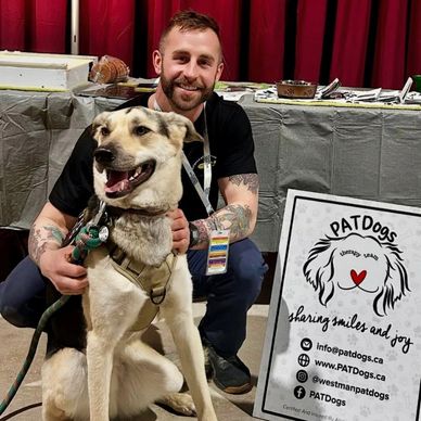 Man with tattoos posing happily with a therapy dog.