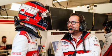 F1 driver and engineer discussing race strategy in the garage.