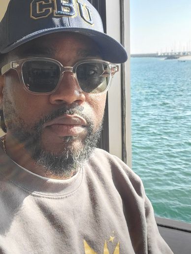 Man with sunglasses and cap near water.