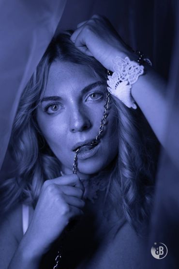 Woman with chain and lace wrist cuff in moody blue lighting.