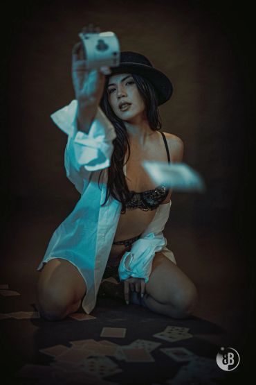 Woman in lingerie and hat playing cards.