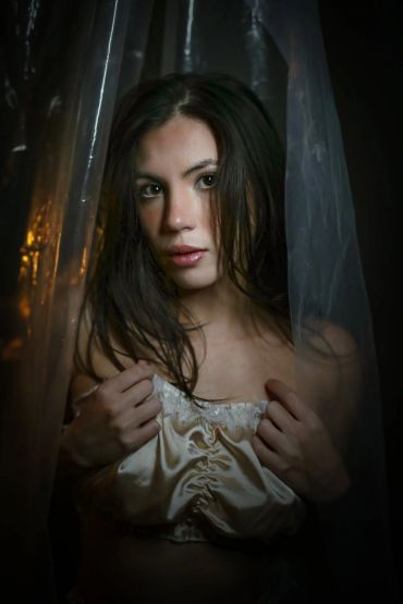 Woman with wet hair behind sheer fabric.