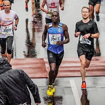 Runners competing in a rainy marathon, crossing the finish line with determination.