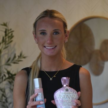 Young woman holding skincare products and smiling.