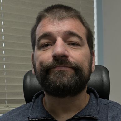 Man with beard sitting in an office chair.